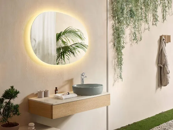 Beleuchteter Antao Spiegel in modernem, beigem Badezimmer Ein modernes Badezimmer mit warmweiß beleuchteten Spiegel, einem grünen Waschbecken und Badmöbeln aus der Kollektion Antao.
