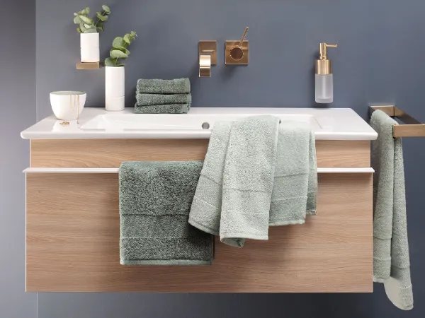 Grüne One Handtücher auf einem Waschbeckenunterschrank Ein Waschbecken mit grünen Handtüchern aus der Kollektion One von Villeroy & Boch und einem Spiegel.