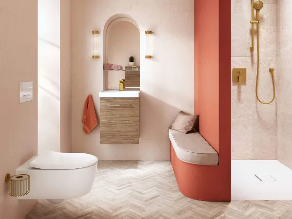 Avento Toilette in korallenfarbenem Badezimmer Modernes Badezimmer mit korallenfarbenen Wänden, einer Trennwand zur Dusche und goldenen Armaturen