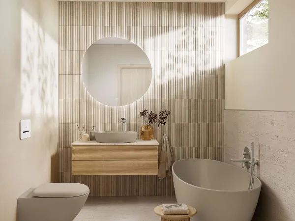 Smalt badrum i All Beige-stil Minimalistiskt badrum med rund spegel, Collaro-handfat, Antao-skåp till tvättställ och dusch i golvnivå. Mjuk belysning och neutrala toner skapar en lugn stämning.