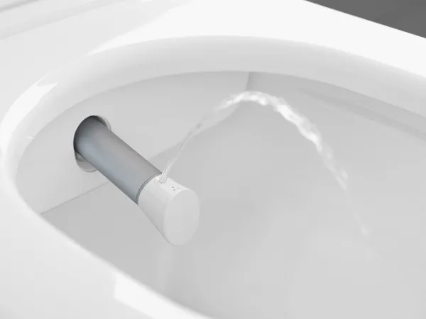 ViClean shower toilet nozzle Close-up of a bidet nozzle spraying water into a toilet bowl. The nozzle is protruding laterally from the toilet rim.
