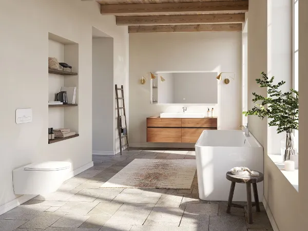 Großes Bad mit weißer Badewanne aus der Kollektion Collaro Ein geräumiges Badezimmer in modernem Design mit Badewanne, Wandtoilette, großem Waschbecken, Holzdecke und großem Fenster. Regale mit Büchern und Dekoration sowie eine Pflanze ergänzen die Einrichtung.