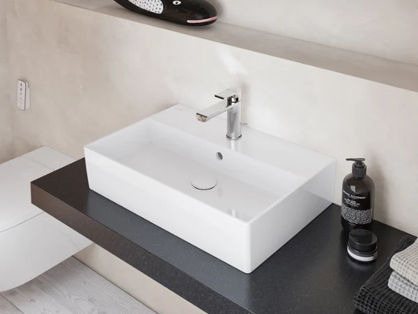 Minimalist Memento 2.0 single washbasin in glossy white, set on a dark countertop with modern chrome tap for a stylish bathroom look.