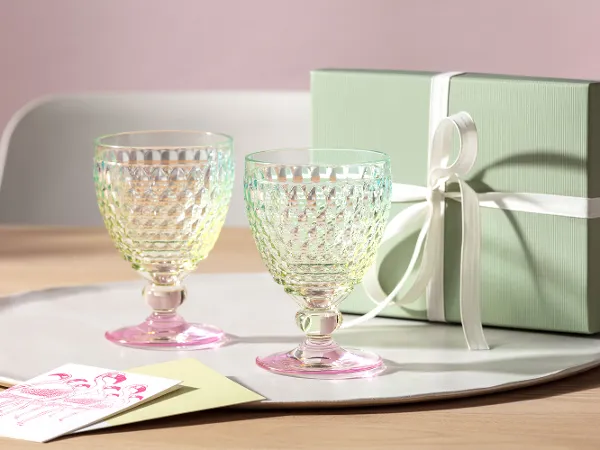 Two Boston Pearl glasses with gift box Two Boston Pearl glasses by Villeroy & Boch stand on a tray on a table next to a light green gift box tied with a ribbon.