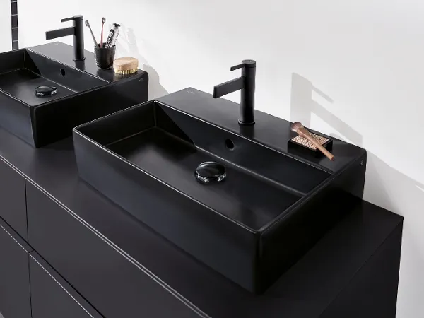 Memento 2.0 Waschbecken mit Dawn Armaturen in Schwarz Zwei schwarze rechteckige Badezimmerwaschbecken von Villeroy & Boch mit mattschwarzen Wasserhähnen auf einer dunklen Arbeitsplatte, ausgestattet mit minimalistischen Badezimmerutensilien.