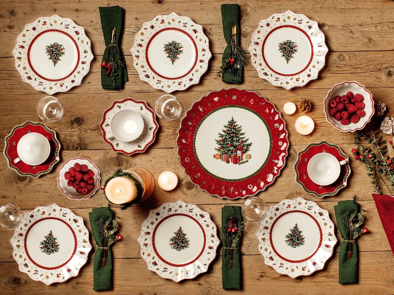 Une table de Noël avec des assiettes Toy’s Delight rouges et vertes et des serviettes Villeroy & Boch.