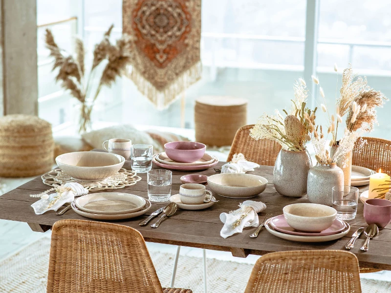 A dining table with rattan chairs and wicker baskets set with Perlemor dinnerware from like. by Villeroy & Boch.