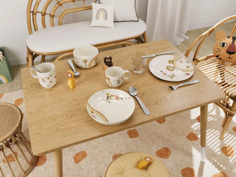 A cosy dining room with a wooden table, wicker chairs and colourful Boho Kids Roar like a Lion children’s crockery.