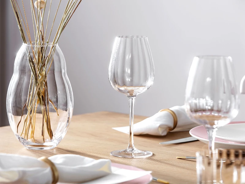 Elegant table decoration with a clear Rose Garden wine glass, a vase with dried stems and fine dinnerware.