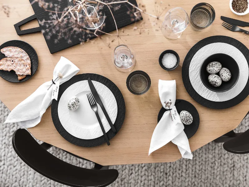 Une table de salle à manger moderne avec de la vaisselle et des couverts de table noirs et blancs de la collection Manufacture ainsi qu’une décoration de Pâques minimaliste.