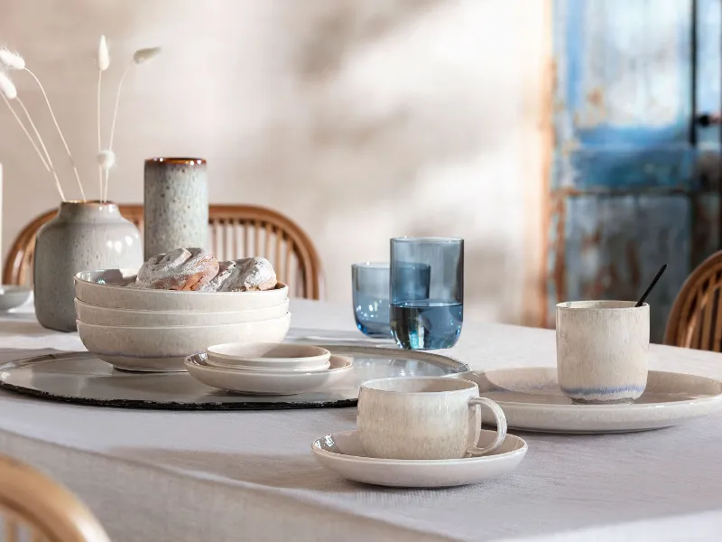 Une table de salle à manger dressée avec des verres bleus de like. Glass et de la vaisselle blanche de la collection Perlemor.