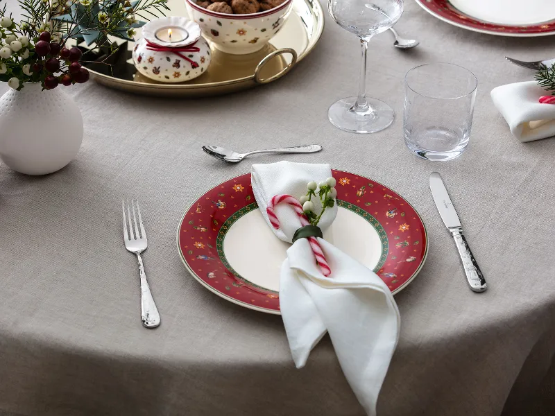 A festive red Toys Delight plate paired with a tealight holder, perfect for a cozy holiday table arrangement.