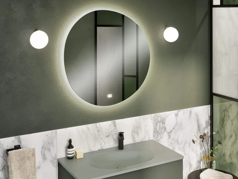 Une salle de bains élégante dans des tons de vert et, avec du marbre, avec un lavabo vert et un miroir lumineux de Villeroy & Boch.