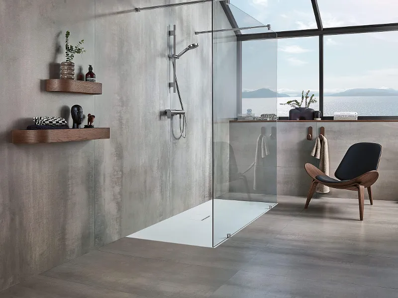 Une salle de bains grise moderne avec un receveur de douche Squaro Infinity et une chaise marron.