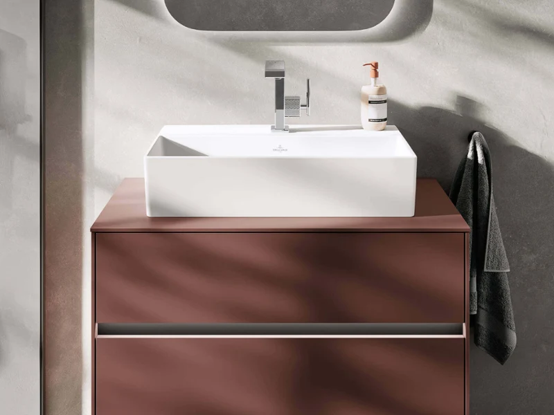 Espace lavabo Collaro moderne dans des tons chauds avec un design minimaliste, doté d'un meuble vasque élancé et de formes géométriques élégantes pour une esthétique de salle de bain intemporelle.