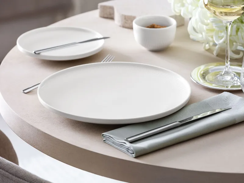 Close-up of an Afina dinner plate with subtle relief on a set table.