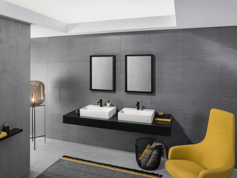 Modern bathroom with two Memento 2.0 washbasins in glossy white, set against dark tiles with yellow highlights for a stylish contrast.
