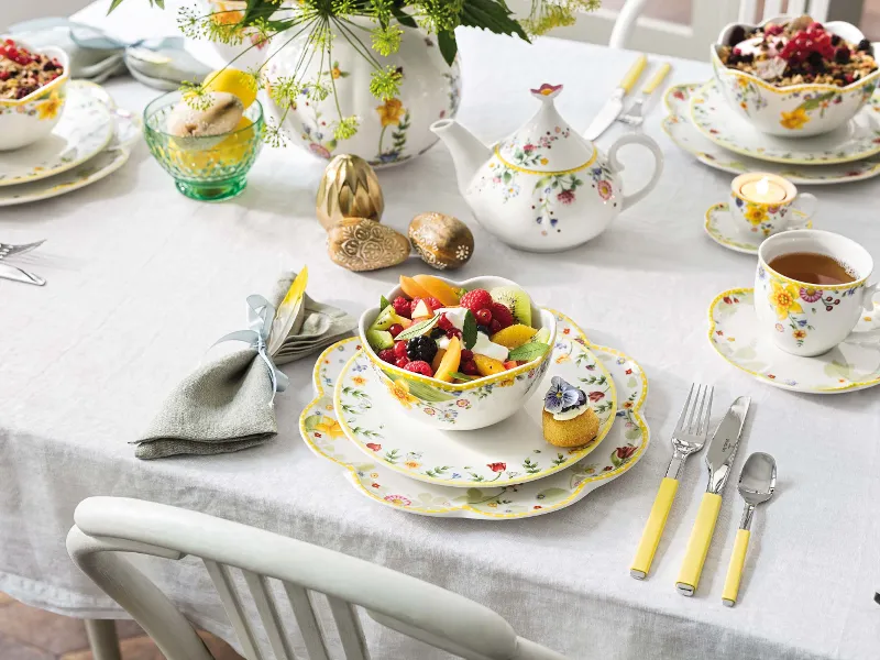 Ein farbenfroher Osterbrunch-Tisch, gedeckt mit floralem Spring Awakening Geschirr und einer Schüssel voller Früchte. 