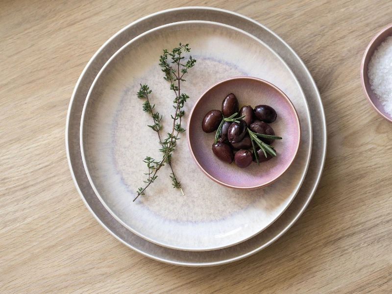 Perlemor borden en dipschaaltjes met olijven en zout op een houten tafel.