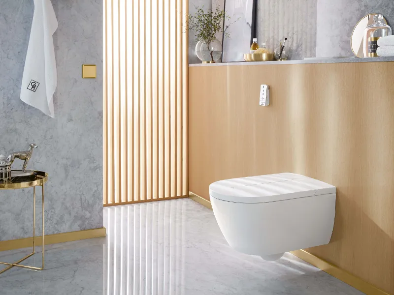 Un WC con doccetta ViClean-I 100 bianco in un bagno grigio.