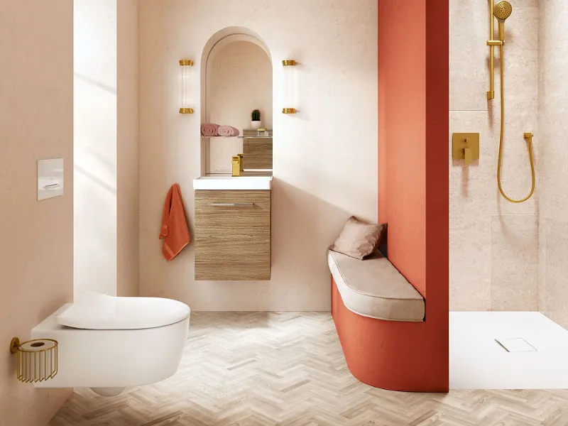 Een badkamer met een oranje muur, witte wastafel en wit toilet uit de collectie Avento van Villeroy & Boch.