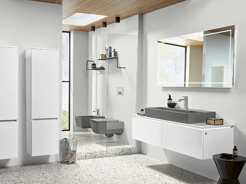 Modernes helles Badezimmer mit weißen Möbeln und hellgraue Kermamikakzenten durch Waschbecken, WC und Bidet von Villeroy & Boch.