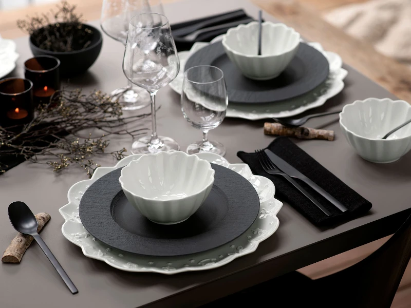 A table set with black Manufacture plates and white Toy’s Delight dinnerware from Villeroy & Boch.