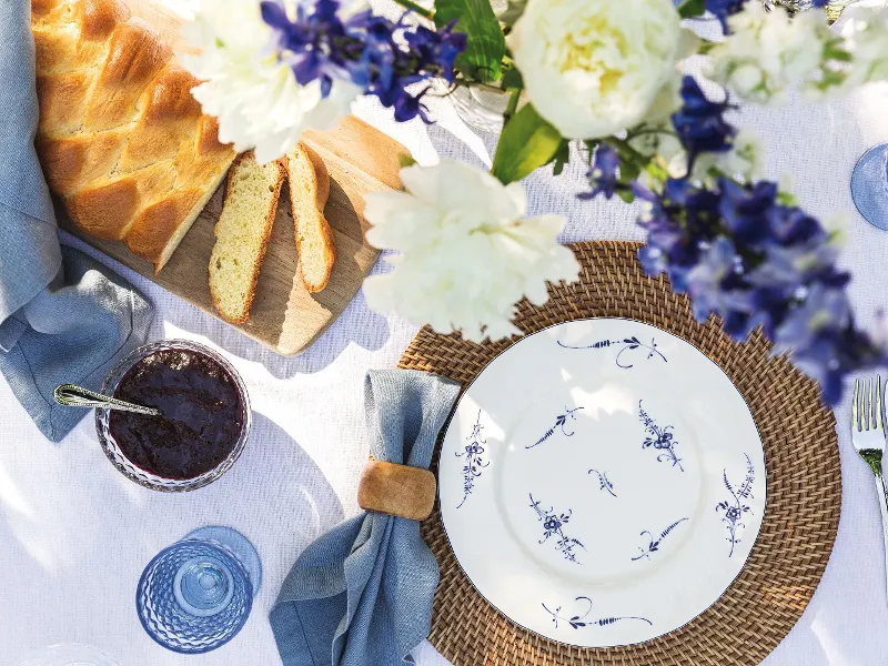 A table is set with a Vieux Luxembourg plate from Villeroy & Boch, a cloth napkin, a knife, a fork, and a jar of dark jam.