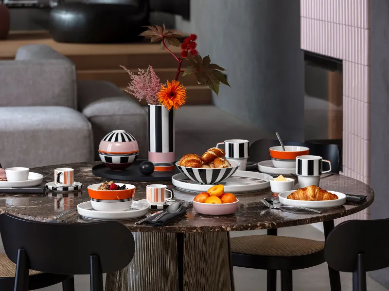 A round breakfast table set with croissants, fruit, coffee and black and white striped crockery from the Memphis collection by Villeroy & Boch.