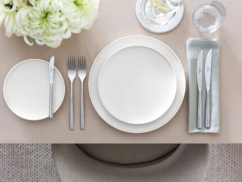 Une table dressée avec des assiettes Afina vues de côté pour voir l’effet aérien des assiettes qui semblent flotter dans l’air.