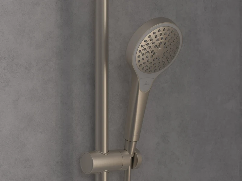 Une douchette à main Verve Shower en chrome classique Un gros plan sur une pomme de douchette à main moderne en chrome, montée sur une barre réglable verticalement devant un mur carrelé gris.