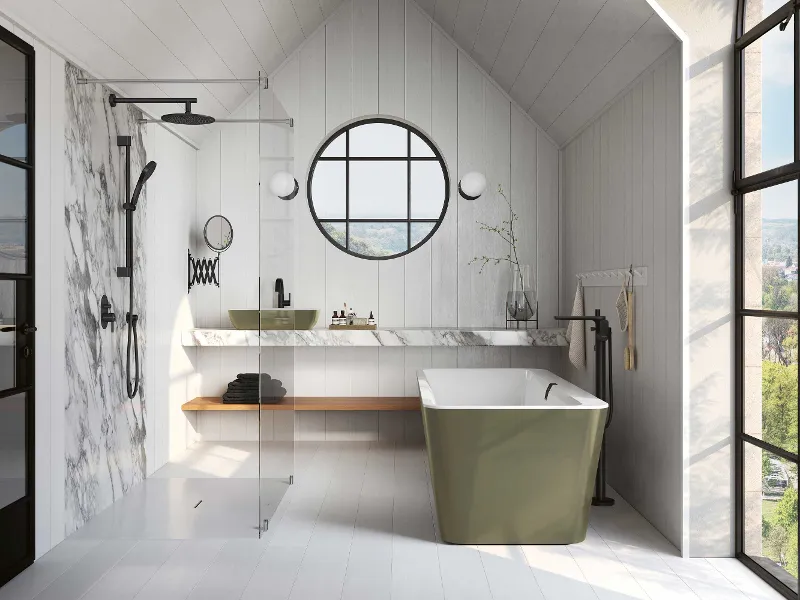 Une salle de bains moderne avec une baignoire en îlot Squaro Edge12 de Villeroy & Boch, une douche à l’italienne, un miroir rond, un double lavabo sur un plan en marbre et un banc en bois. L’équipement comprend des serviettes, des articles de toilette et une grande plante dans un vase.