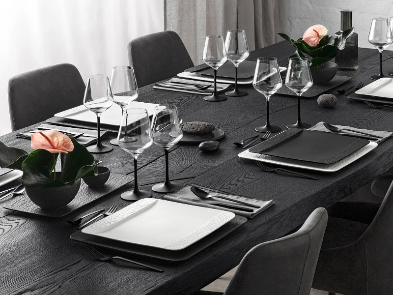 A black table set with glasses, rectangular dinnerware and flatware from the Manufacture collection by Villeroy & Boch.