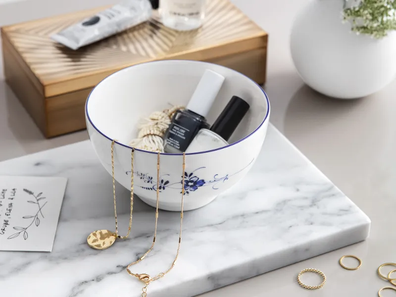 Elegant bathroom corner with skincare products, jewelry and fresh flowers with an Old Luxembourg porcelain serving bowl.