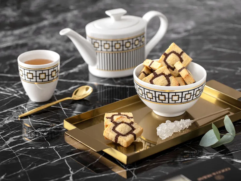 Elegant MetroChic tea set with a teapot and a cup on a gold tray, on a marble table.