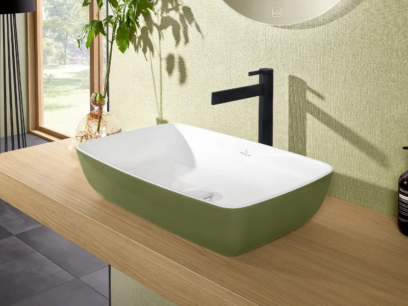 Lavabo moderno rettangolare su un piano in legno in un bagno con una parete d'accento verde