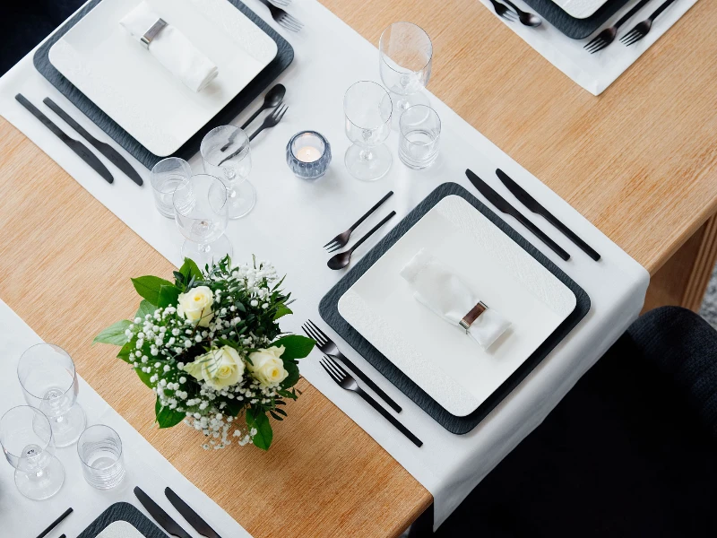 A set table with square Manufacture plates in black and white with NewMoon glasses.