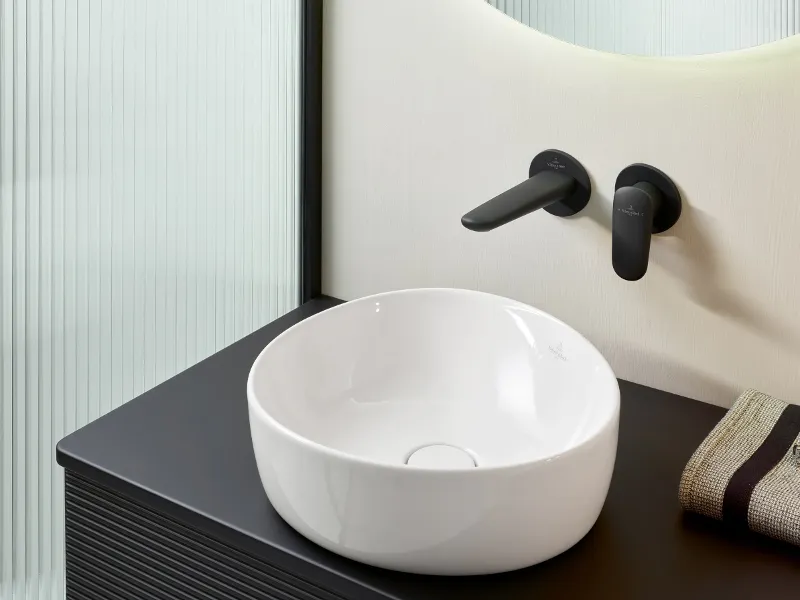 Moderna zona lavabo Antao di Villeroy & Boch in bianco e nero con lavabo freestanding con miscelatore nero opaco e specchio.