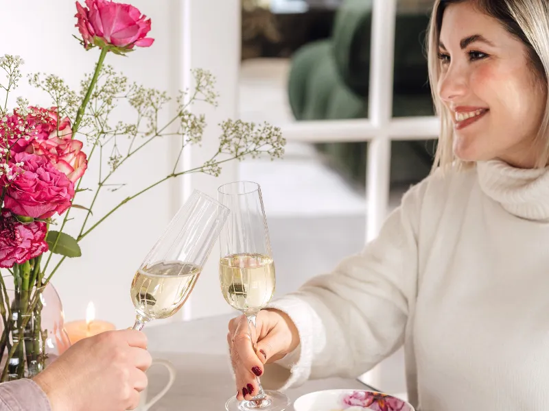 a woman having brunch with a man and toasting with champagne glasses