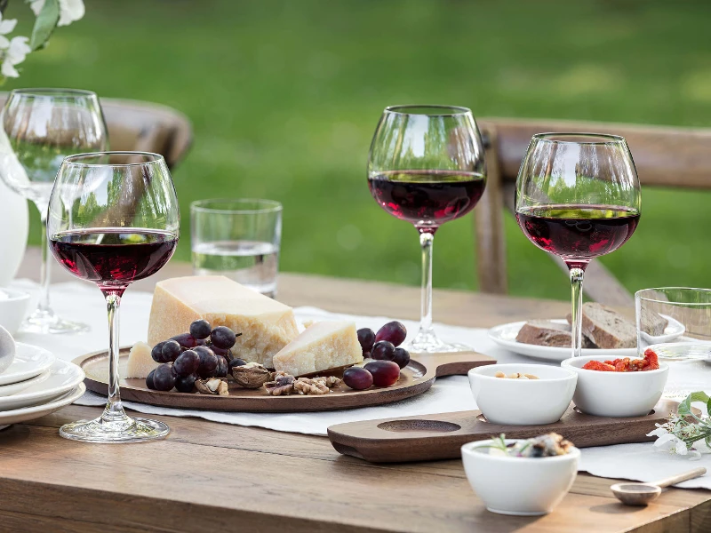 Une table avec des verres à vin rouge Purismo ainsi que des coupelles à dips et un plateau d’antipasti Artesano.