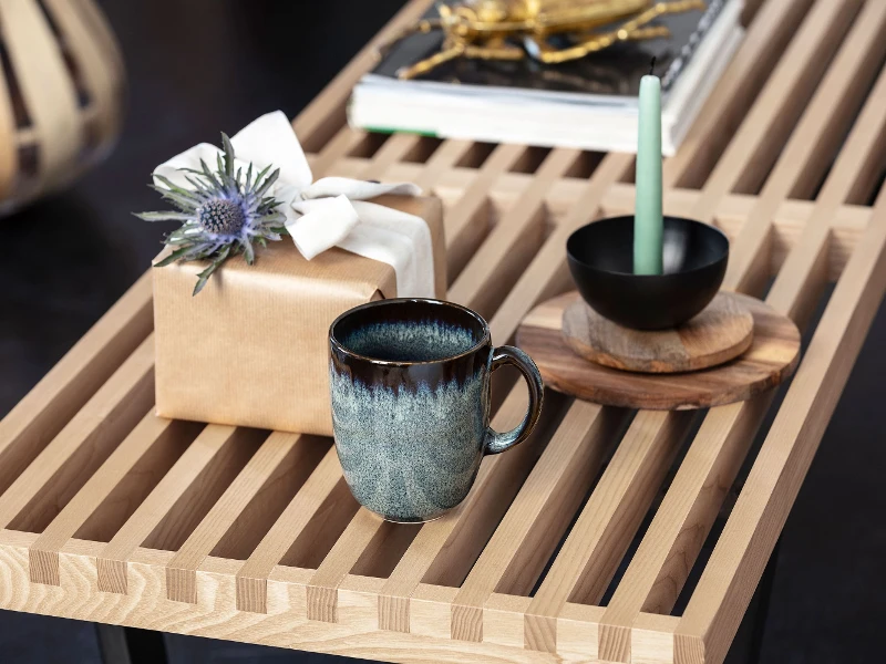 Lave mug, a gift box with a bow and a bowl on a wooden tray, on an elegant table.