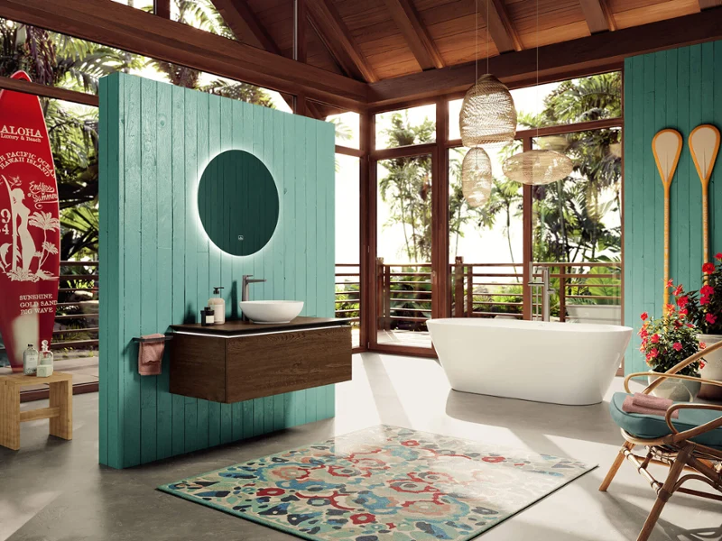 Luxurious bathroom with a large More to See mirror and a white Loop & Friends washbasin in front of a turquoise-coloured wall, surrounded by lush greenery visible through the full-length windows