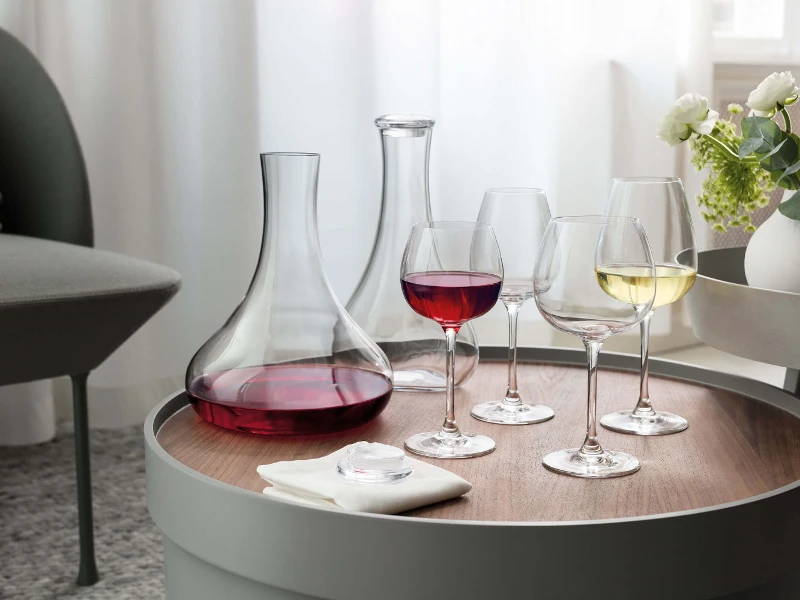 Two Purismo wine decanters with various Purismo wine glasses, filled with red and white wine, on a table.