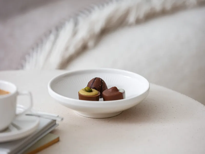 Afina dipschaaltje van Villeroy & Boch gevuld met chocolaatjes op een beige salontafel.