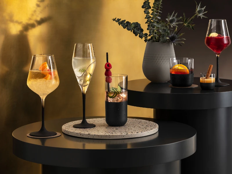 Verschiedene Cocktails, elegant präsentiert in Manufacture Gläsern auf einem modernen Bartisch mit stimmungsvoller Beleuchtung.