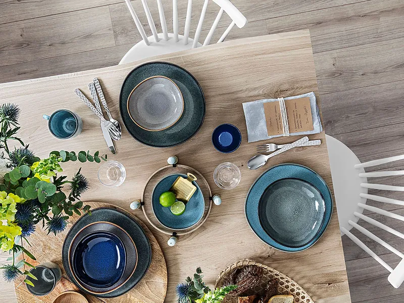 Une table en bois avec des assiettes Lave de Villeroy & Boch posées dessus.