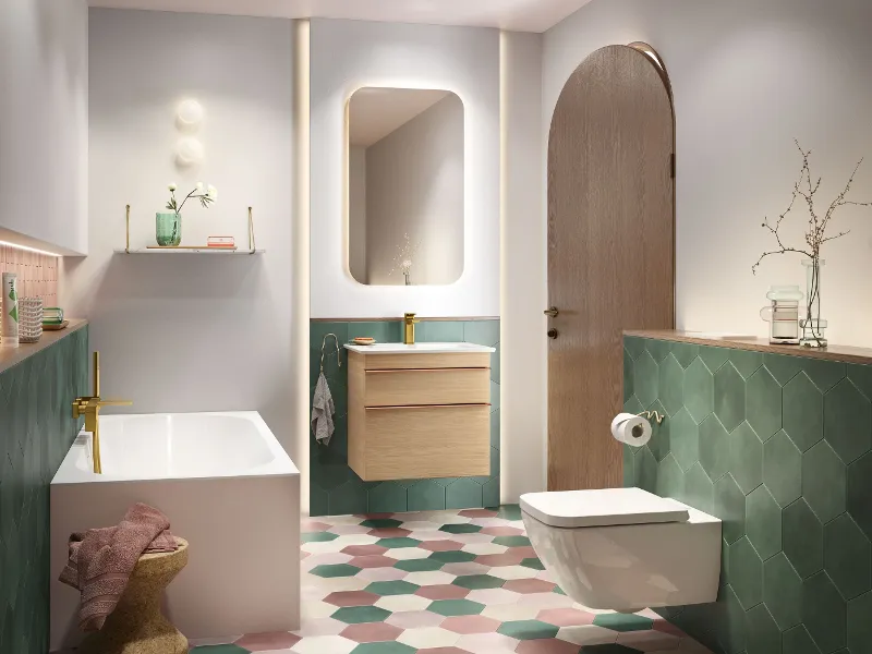 Un bagno moderno con vasca, lavabo sospeso con specchio e WC sospeso. La stanza è dotata di piastrelle esagonali nei colori verde, rosa e bianco.