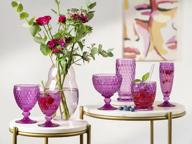 Elegante decorazione da tavolo con bicchieri Boston rosa con bevande e un vaso con fiori su uno sfondo dai toni tenui con arte astratta.	