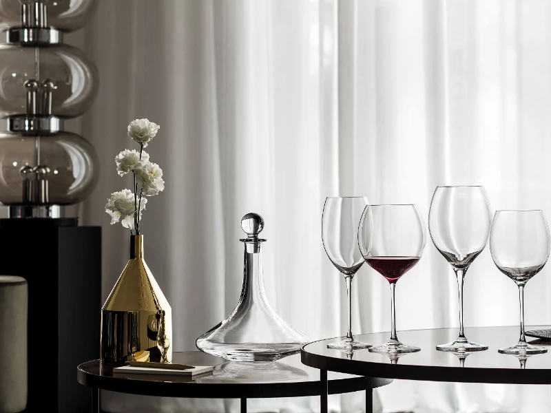 Some Allegorie wine glasses, filled with red wine, on a table with an elegant Vinobile wine decanter.