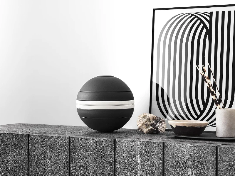 There is a black and white La Boule Stripe from Villeroy & Boch on a sideboard.